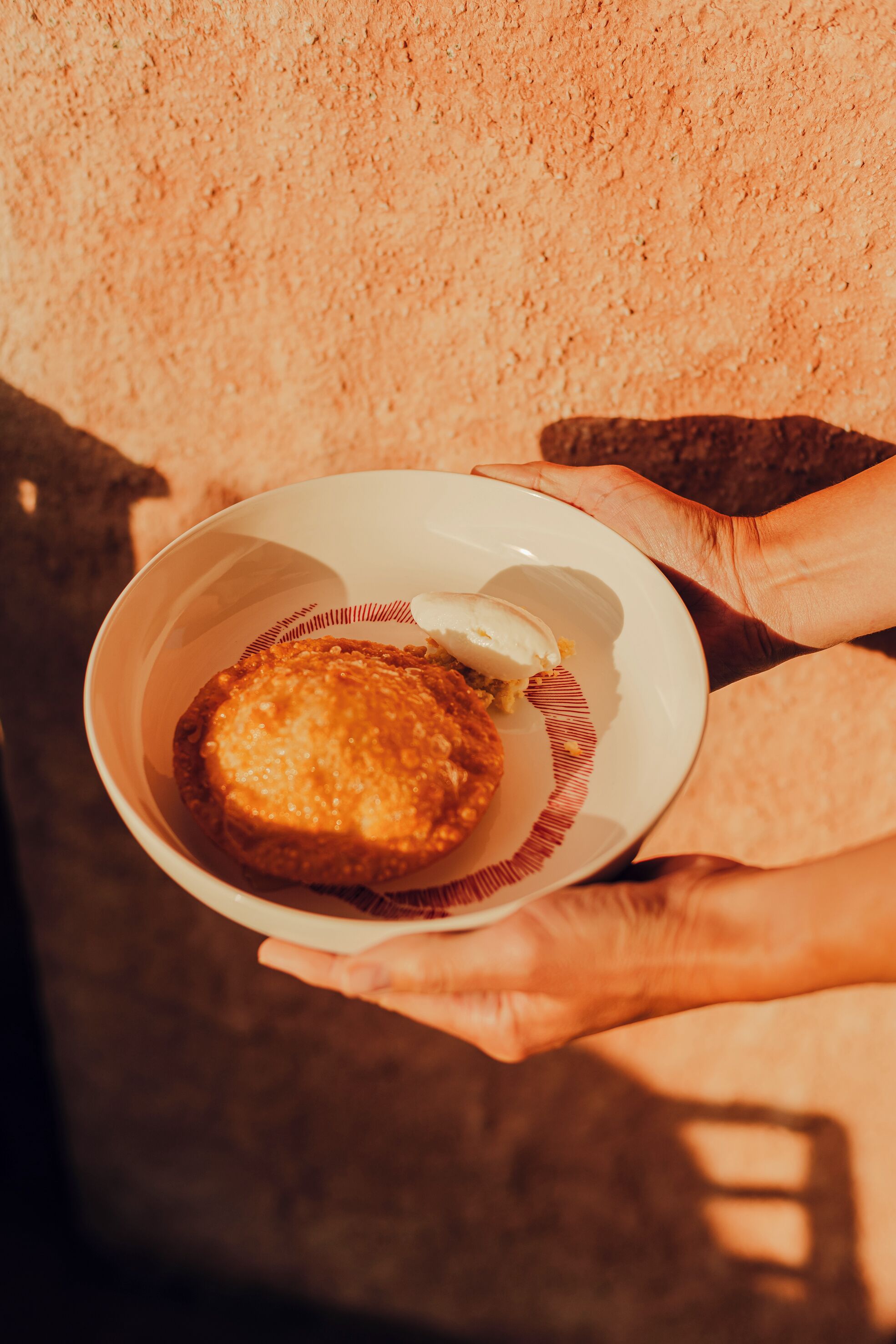 Una persona sosteniendo un tazón con comida y una bola de helado.