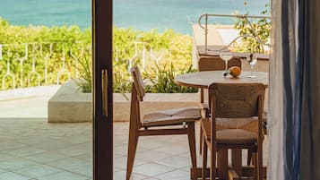 Une chambre avec vue sur la mer, une table avec des chaises et un verre à boire.