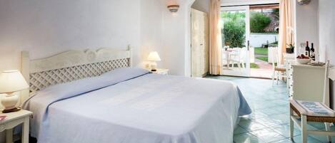 Un dormitorio con una cama grande, una mesita de noche, una lámpara y vistas a un patio exterior.