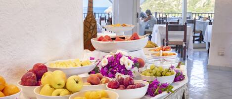A buffet table with various fruits and flowers.