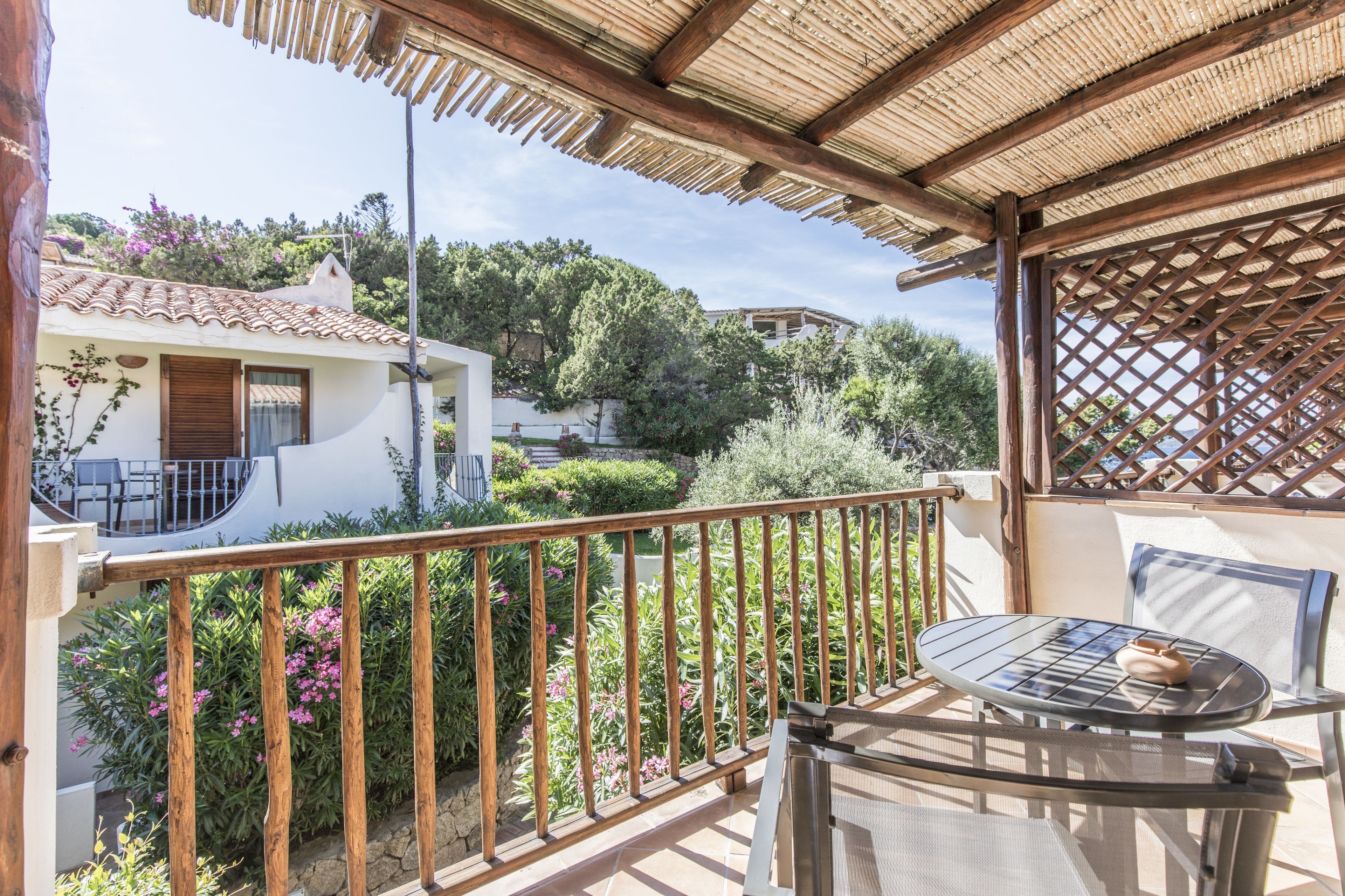 A balcony with a wooden railing, a glass table, and a chair.