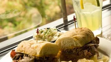 A plate with a sandwich, chips, and a drink with a straw and lime.