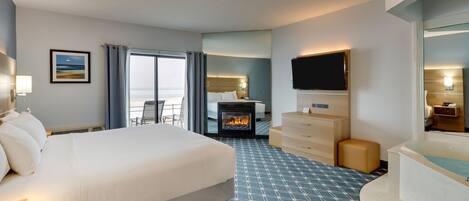 Ein Hotelzimmer mit einem großen Bett, einem Kamin, einem Fernseher, einem Schreibtisch und Meerblick.