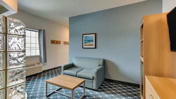 A room with a patterned floor, a light blue sofa, a wooden table, and a framed picture on the wall.