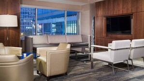 Ein modernes Hotelzimmer mit einer Couch, Sesseln, einem Couchtisch und einem Fernseher.