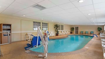 Una piscina interior con una silla de salvavidas, una escalera y un tendedero para toallas.