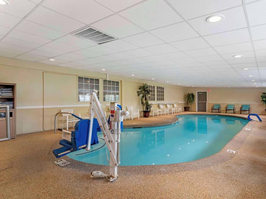 Una piscina interior con una silla de salvavidas, una escalera y un tendedero para toallas.