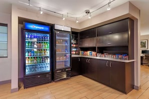 Un espace de vente proposant des distributeurs automatiques de Pepsi et de Coca-Cola, des distributeurs de collations et un comptoir où sont exposés des produits emballés.