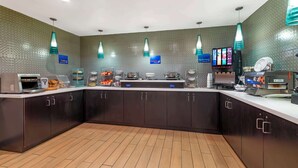A modern kitchen area with a central counter, various appliances, and hanging lights. - Best Western York Inn (York)