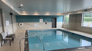 Une piscine intérieure à l’eau claire, avec une bouée de sauvetage et un panneau indiquant « Il est interdit de plonger » sur le mur.