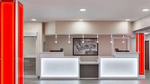 A reception area with two white reception desks, a framed welcome sign, and a herringbone-patterned floor.