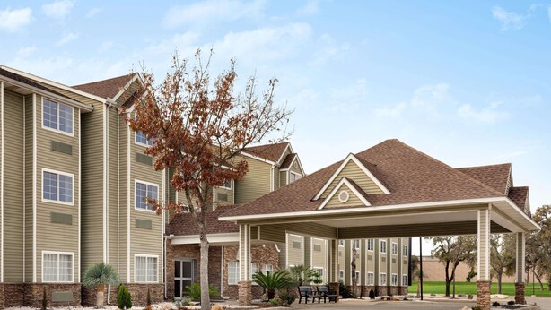 A multi-story hotel with a covered entrance, stone accents, and a landscaped driveway.