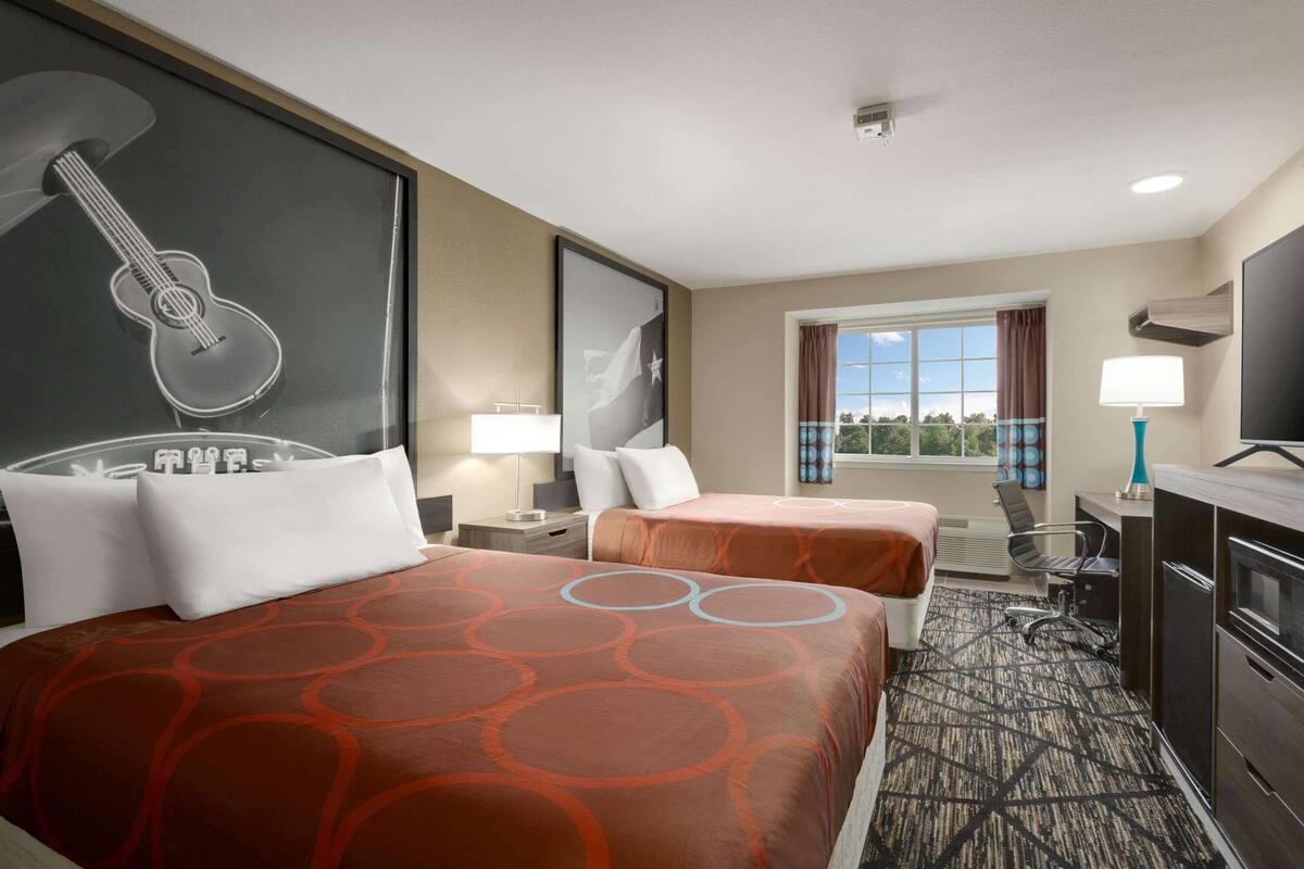 Une chambre d’hôtel avec deux lits, un bureau, une télévision et une fenêtre donnant sur un paysage agréable.