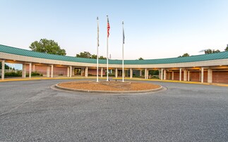 Un edificio con techo verde y un letrero que dice "Kentucky Dam Village". Hay tres mástiles con banderas en la parte frontal del edificio.