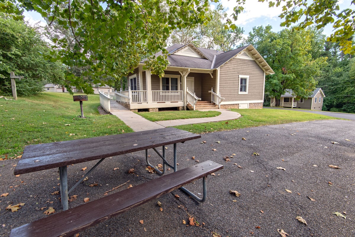 Ett bostadshus med en veranda, en uppfart och ett picknickbord framför.