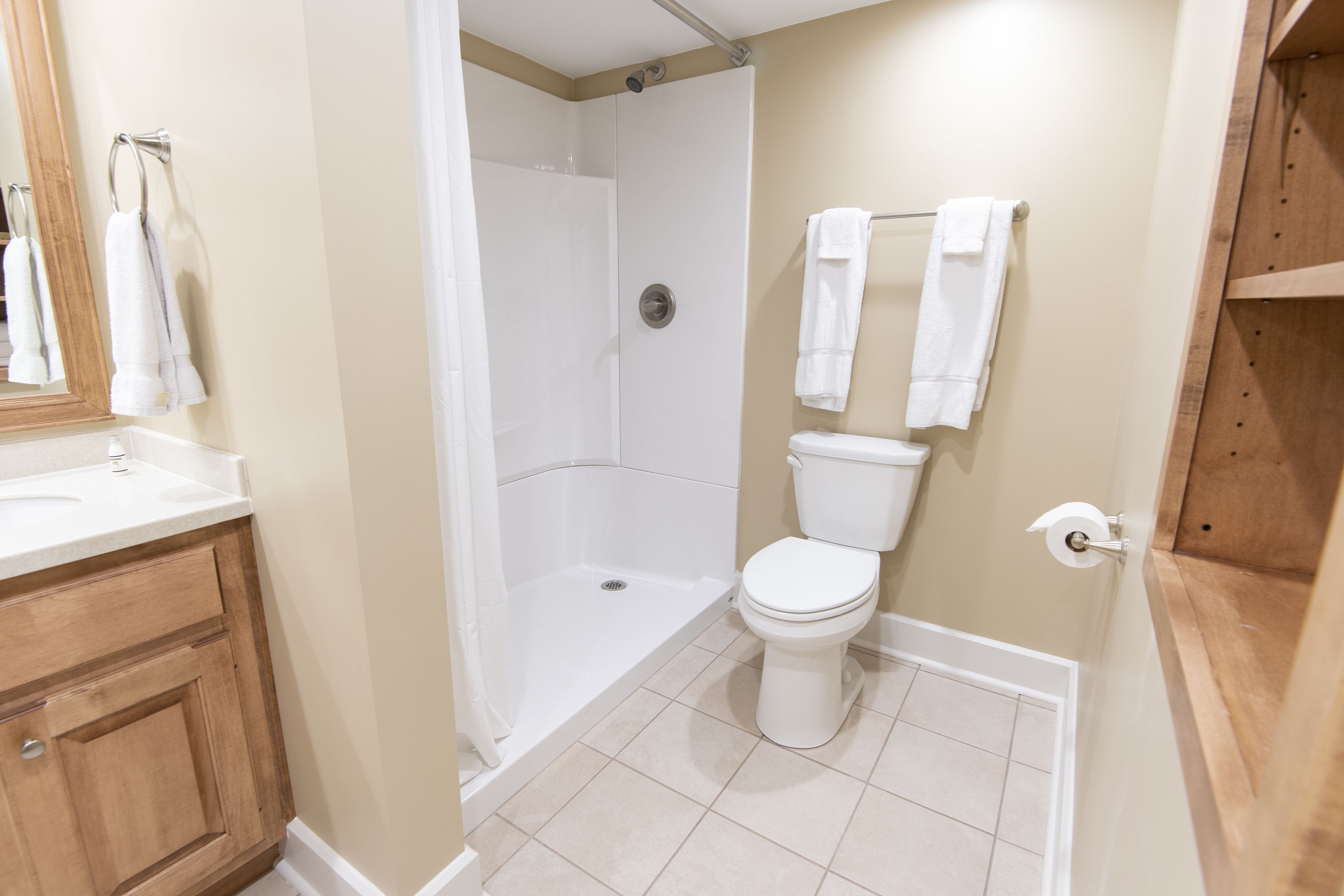 Un bagno con doccia, WC e mobile lavabo in legno.