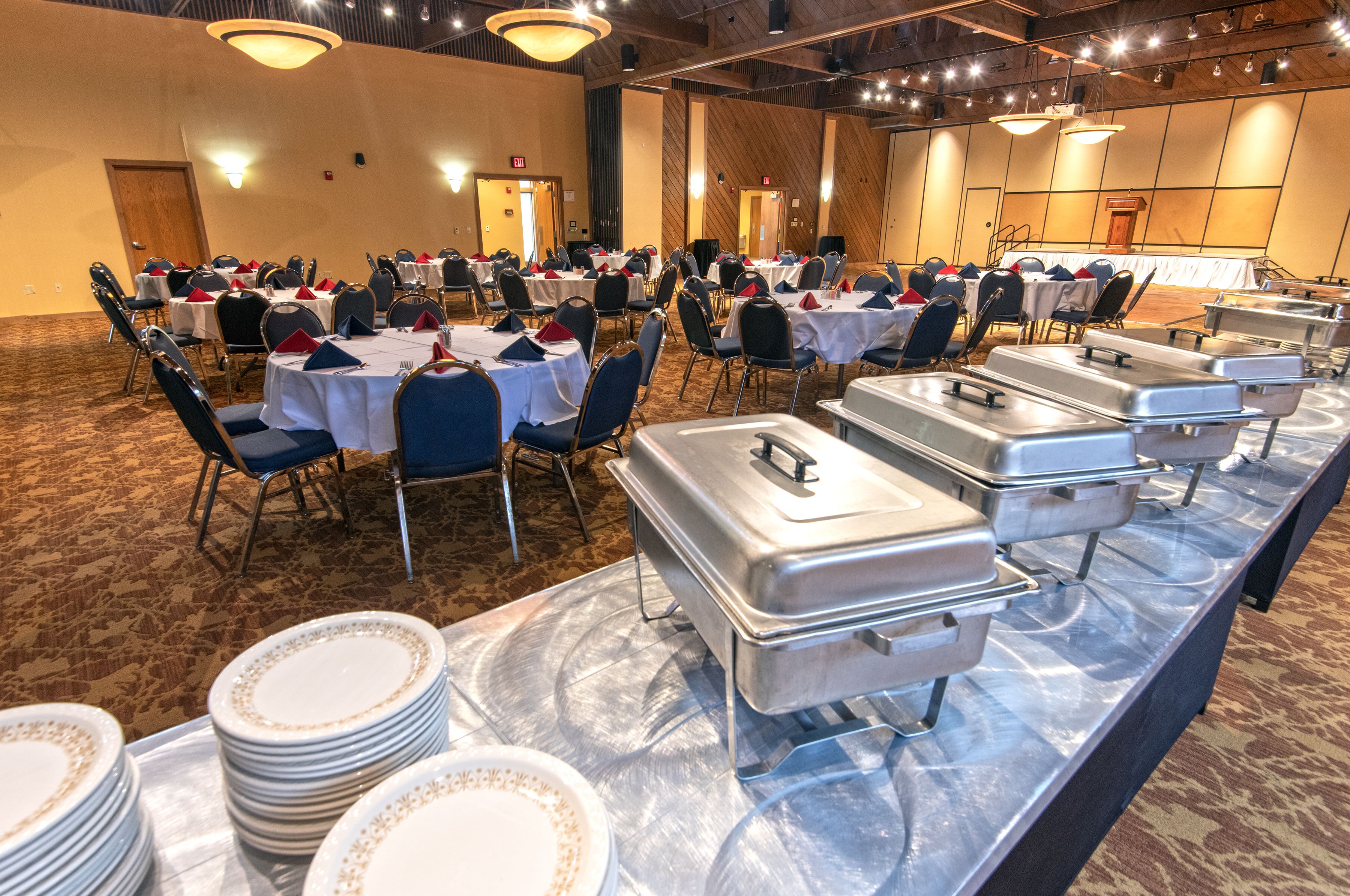 A banquet hall with round tables, chairs, and buffet stations.