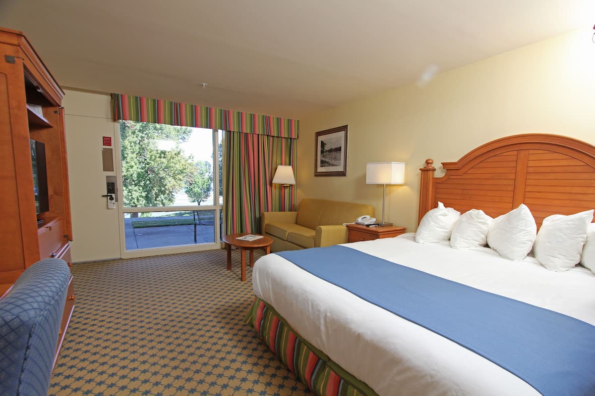 Ett hotellrum med en stor säng, en soffa, ett skrivbord och ett fönster med gardiner.