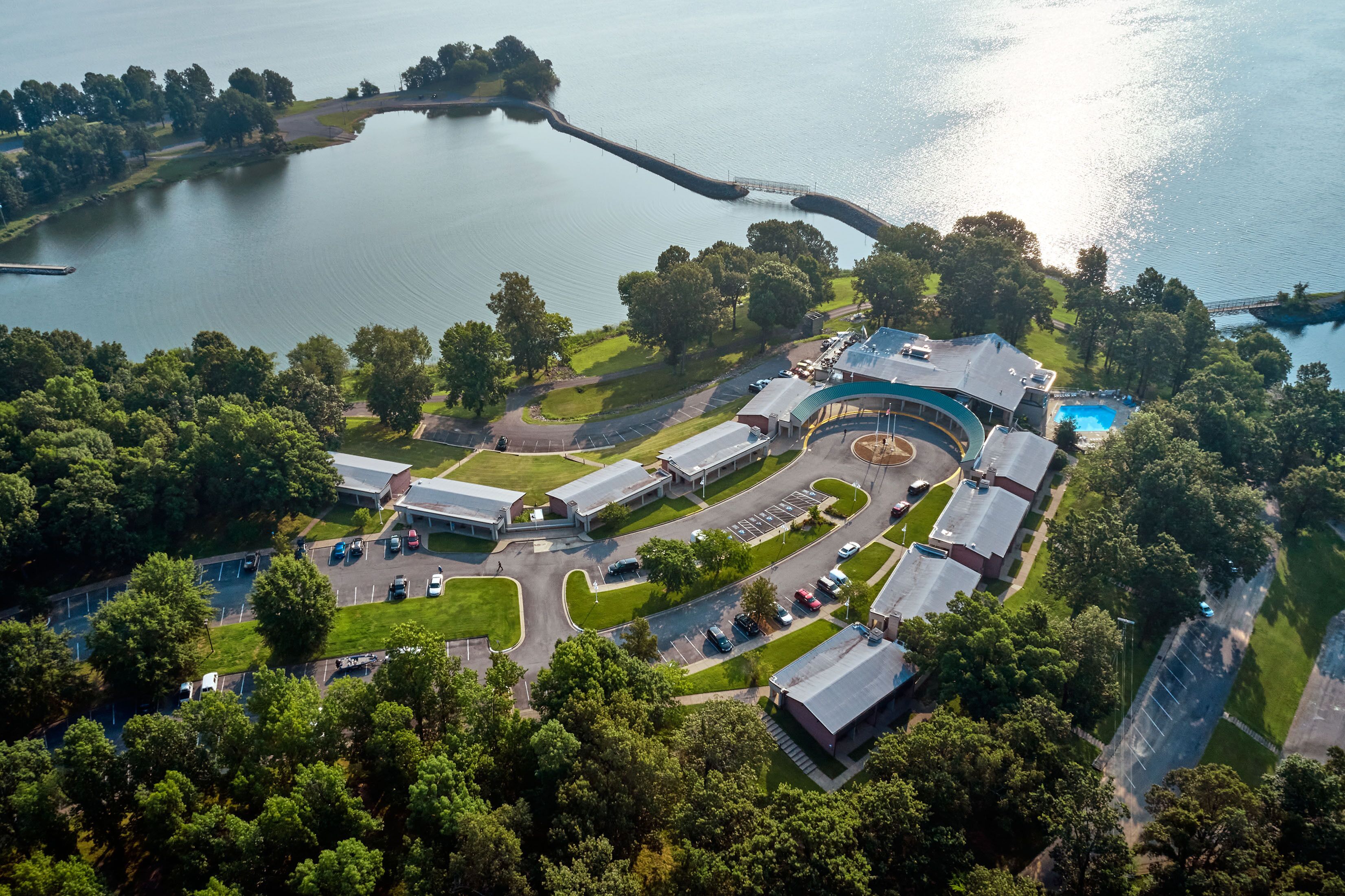 An aerial view of a hotel with multiple buildings, a parking lot, and a lake.