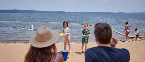 Escena de playa con gente jugando con frisbees y nadando.