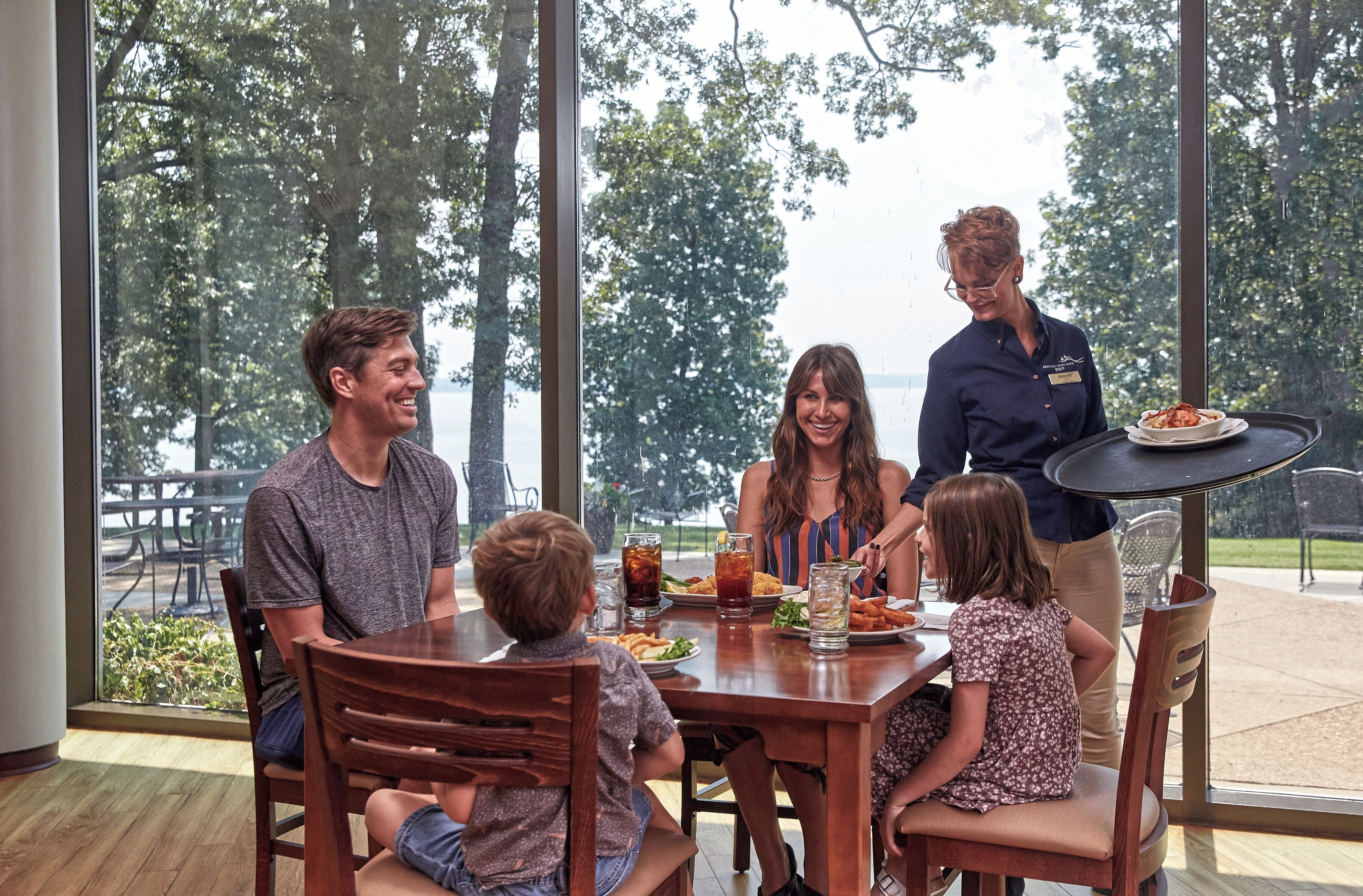 A family dining at a table with a view of trees and a patio area.