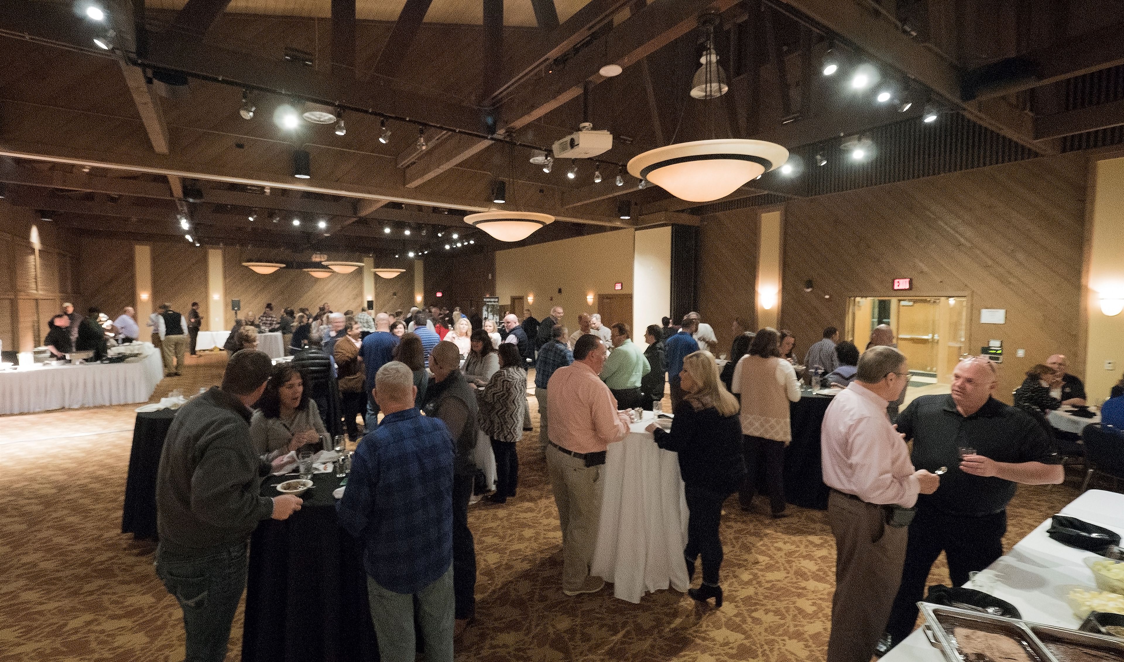 A large indoor event space with high ceilings, chandeliers, and tables set up for dining.