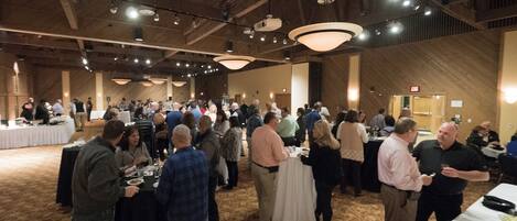 A large indoor event space with high ceilings, chandeliers, and tables set up for dining.
