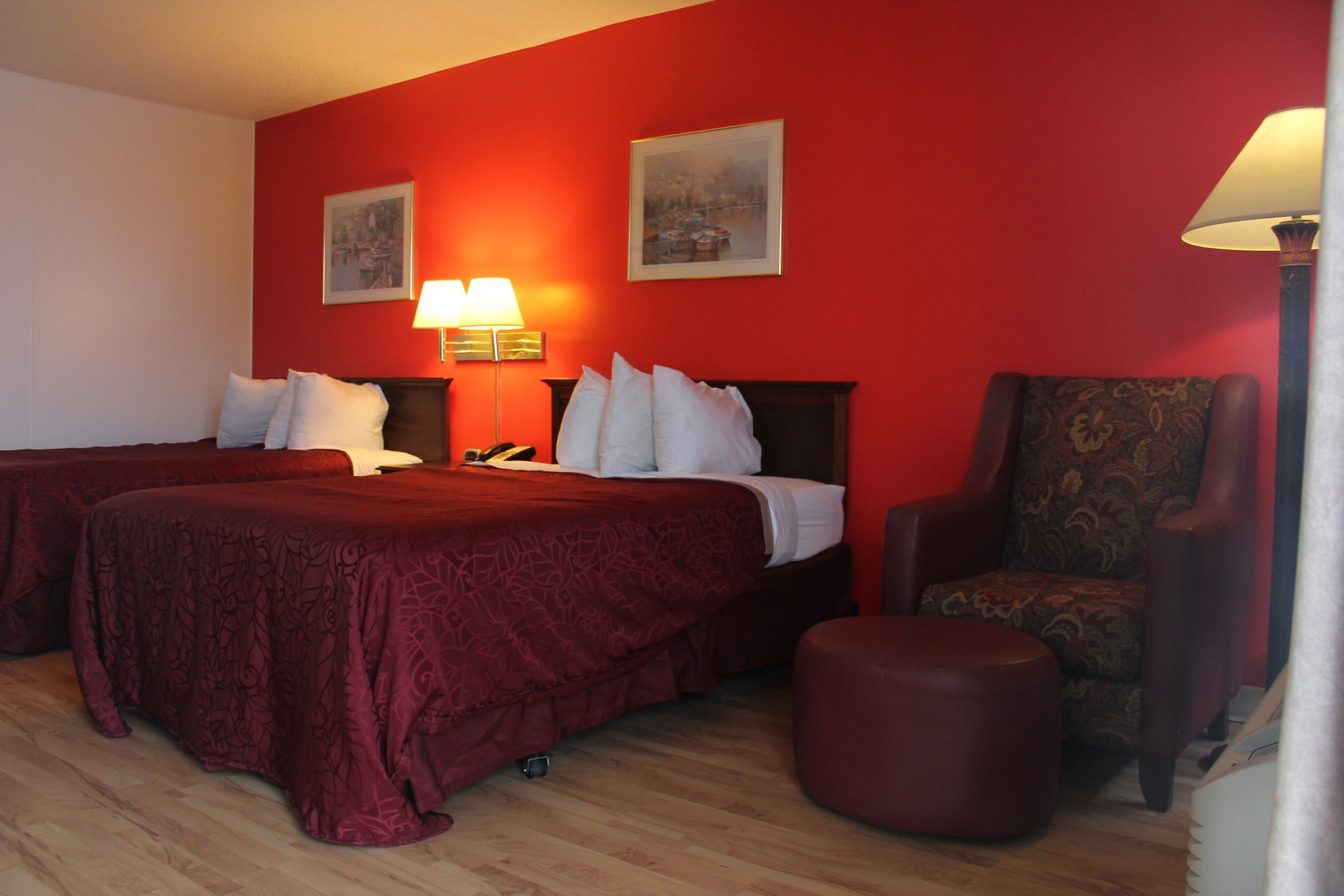 Habitación de hotel con dos camas, una silla y una lámpara.