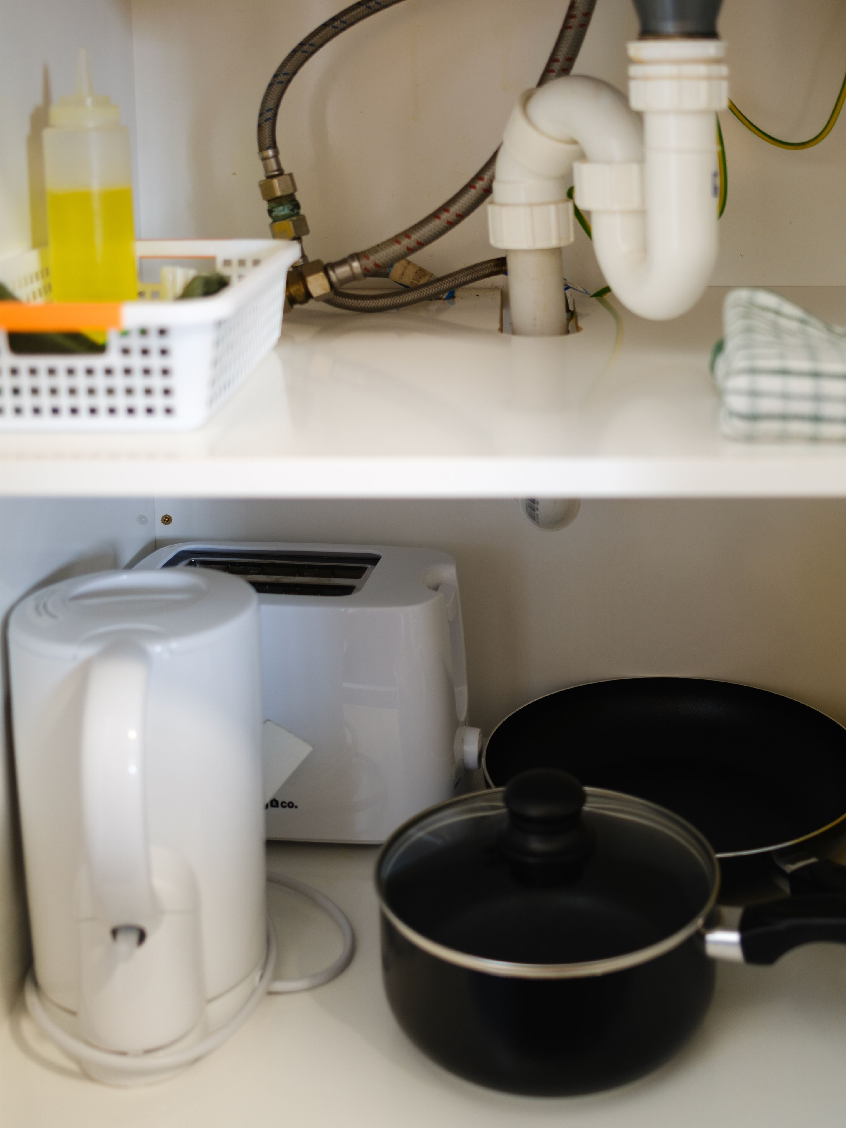 Uma cozinha com uma cafeteira, uma torradeira e uma frigideira sobre o balcão.
