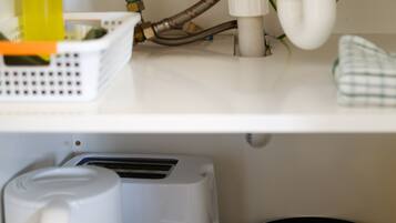 Uma cozinha com uma cafeteira, uma torradeira e uma frigideira sobre o balcão.