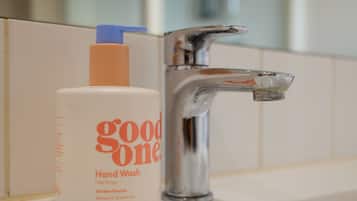 A bathroom sink with a bottle of hand wash soap labeled "good one" and a chrome faucet.