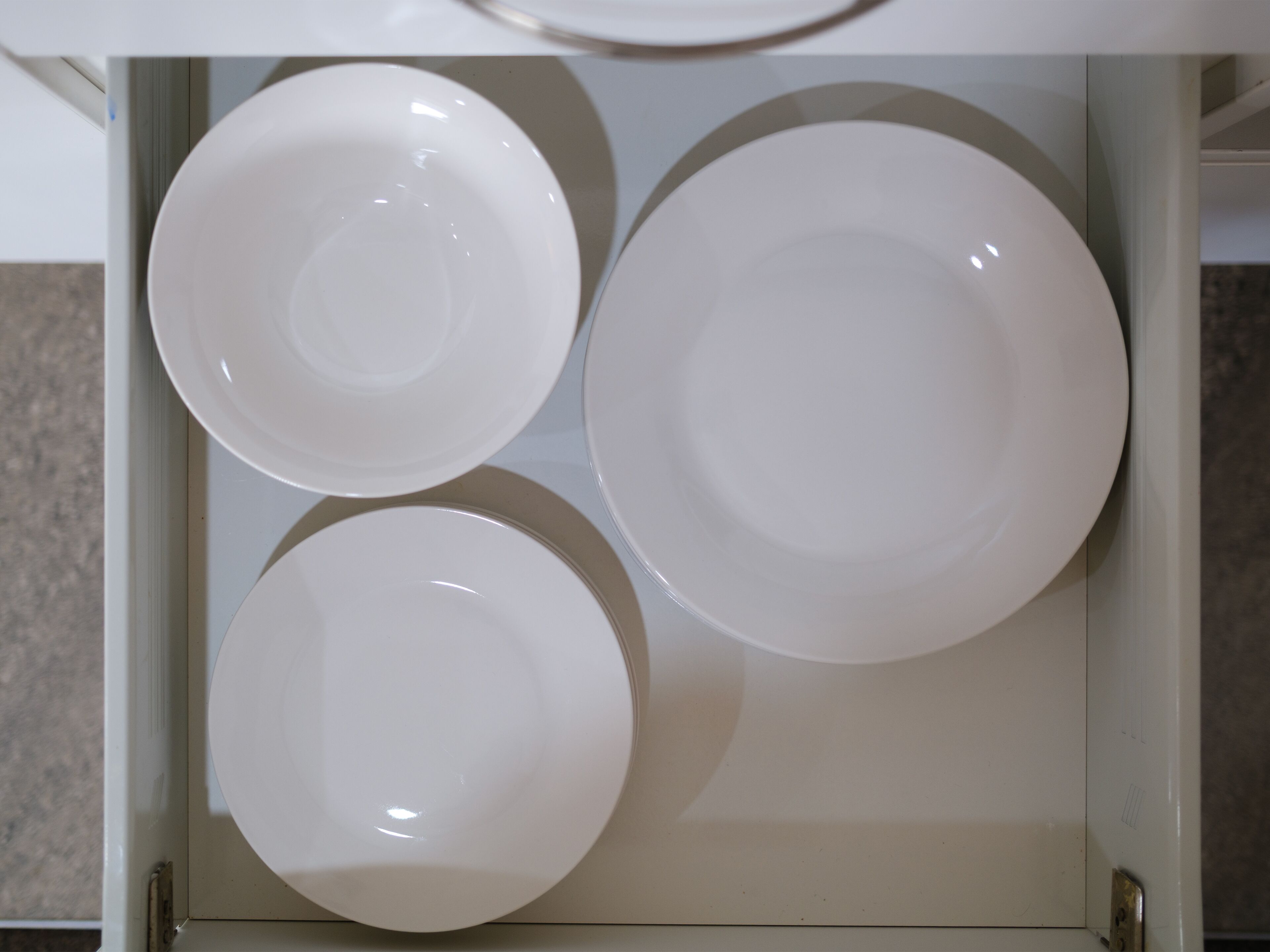 A drawer with three white plates.