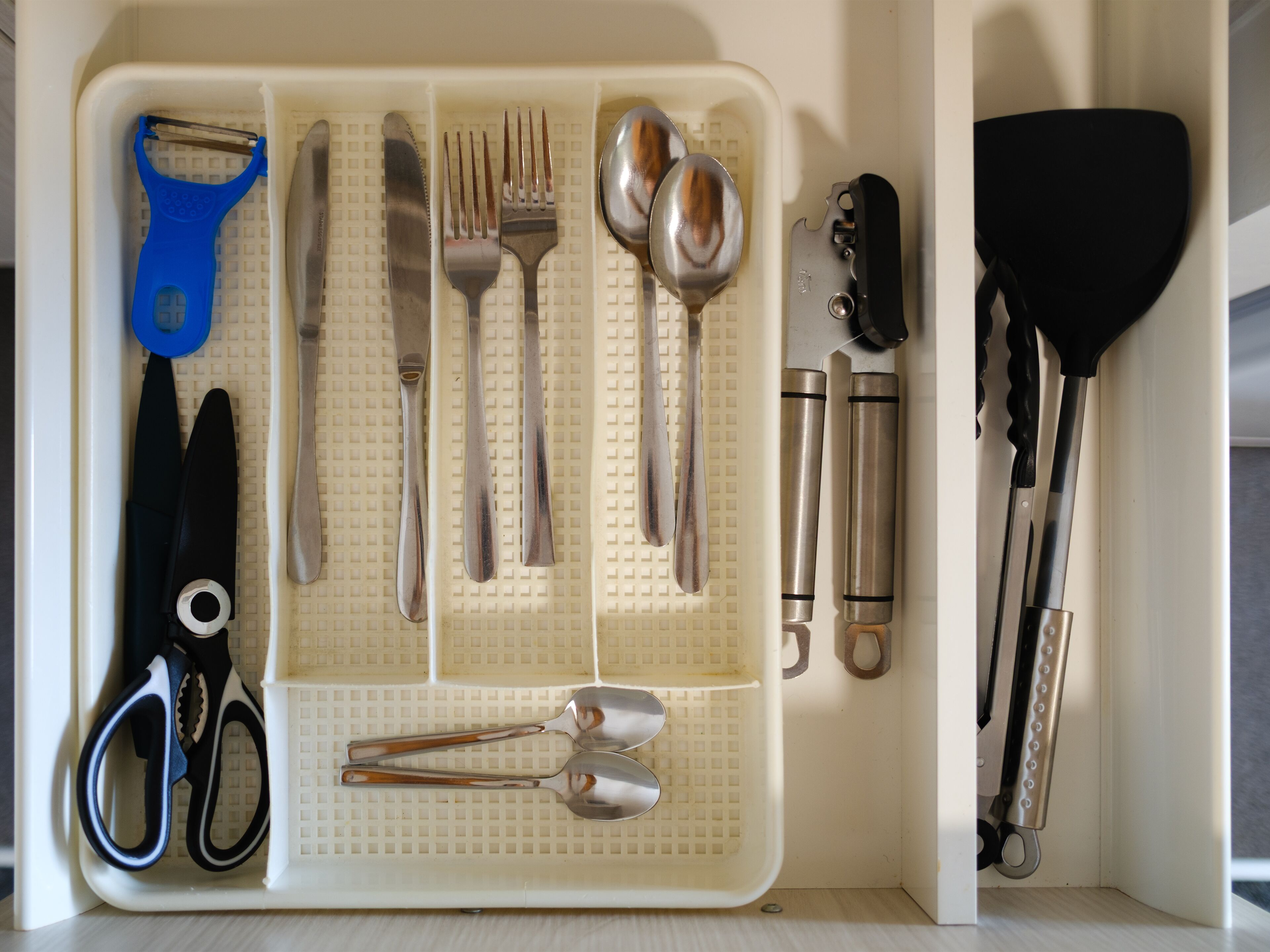 Un organizador de utensilios de cocina con diversas herramientas como tijeras, pinzas y una espátula.