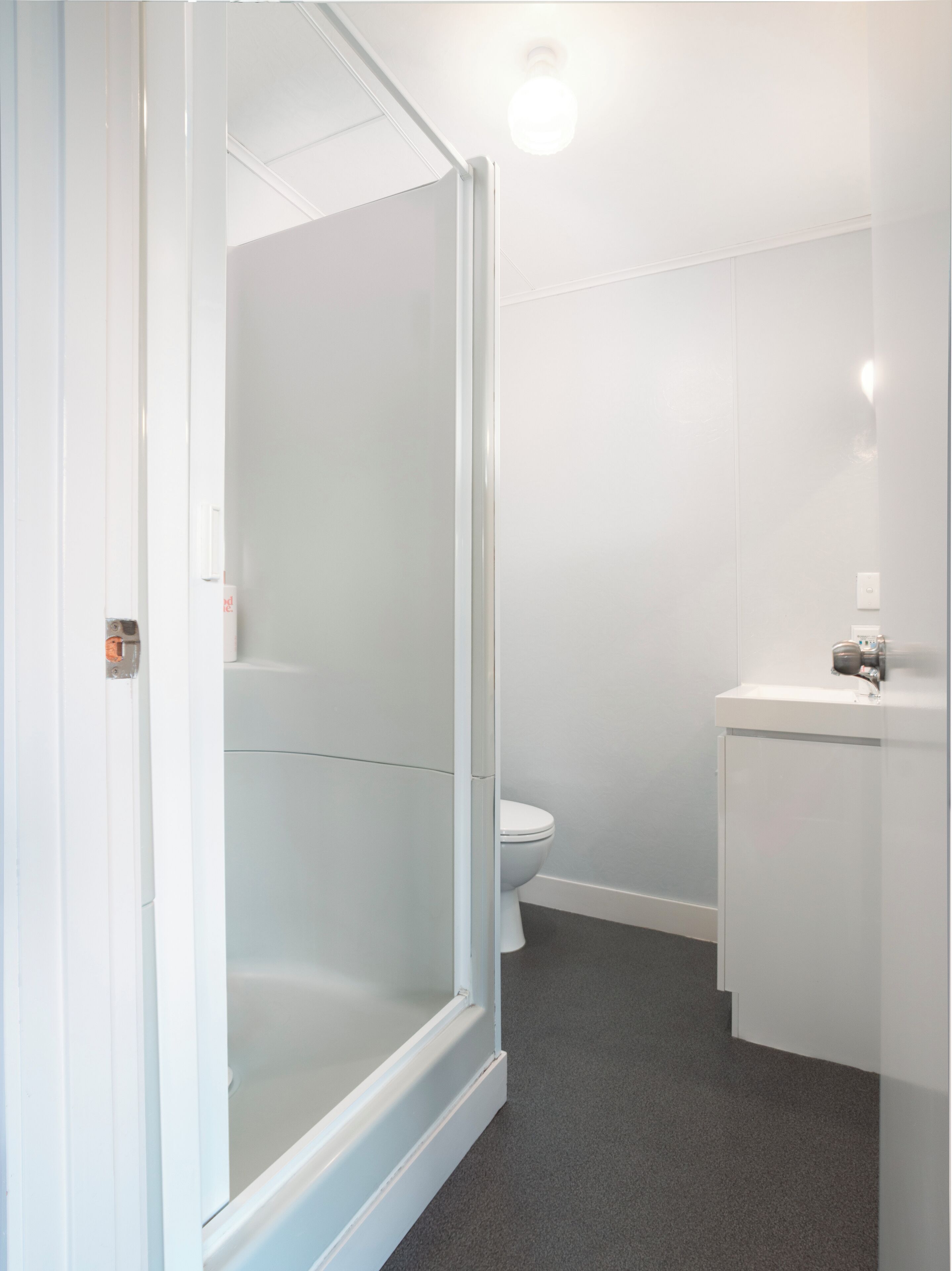 A bathroom with a shower enclosure, toilet, and sink.