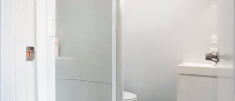 A bathroom with a shower enclosure, toilet, and sink.