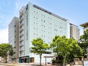 Un hotel moderno con varios pisos, una entrada destacada y un área de estar al aire libre techada.