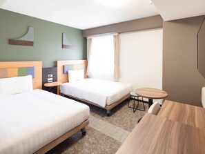 Een hotelkamer met twee bedden, een klein rond tafeltje, een stoel en een raam met gordijnen.