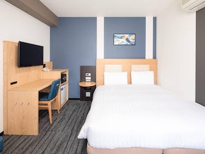 Une chambre d’hôtel comprenant un lit, un bureau avec une chaise, une télévision, une petite table et une œuvre d’art accrochée au mur.