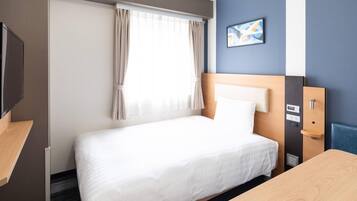 A hotel room with a bed, a desk, a TV, and a window with curtains.