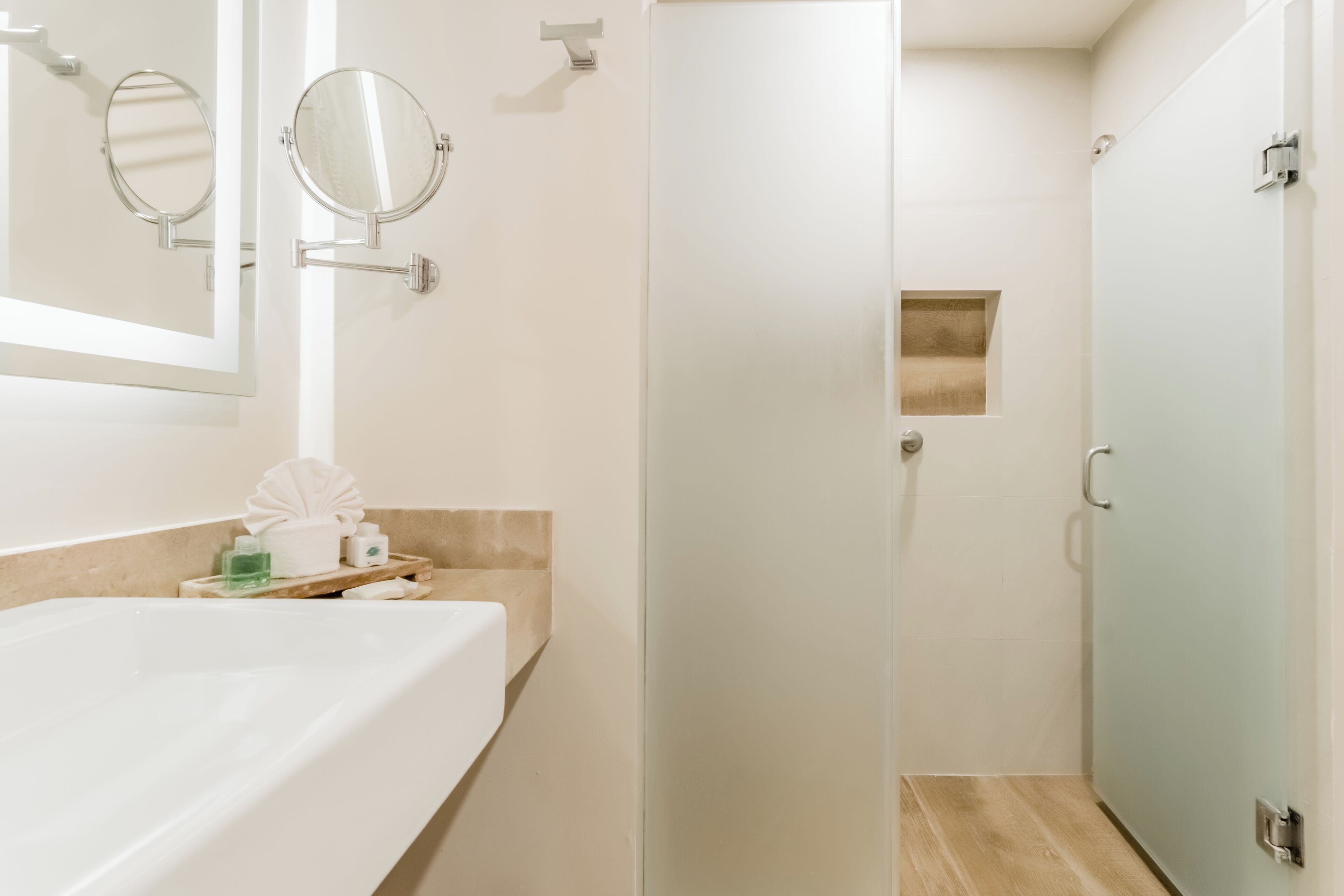 A bathroom with a bathtub, two wall-mounted mirrors, a towel rack, and a shower door.