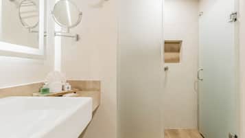 Bagno con vasca, due specchi a muro, portasciuga e una porta per la doccia.