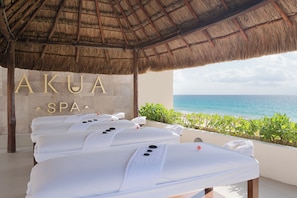Un área de spa con techo de paja, un letrero que dice 'AKUA SPA' y vista al océano.