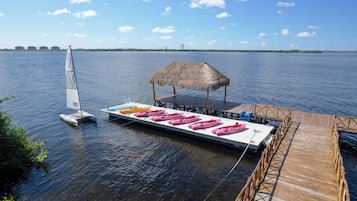 Un muelle con una estructura de techo de paja y un bote con kayaks.