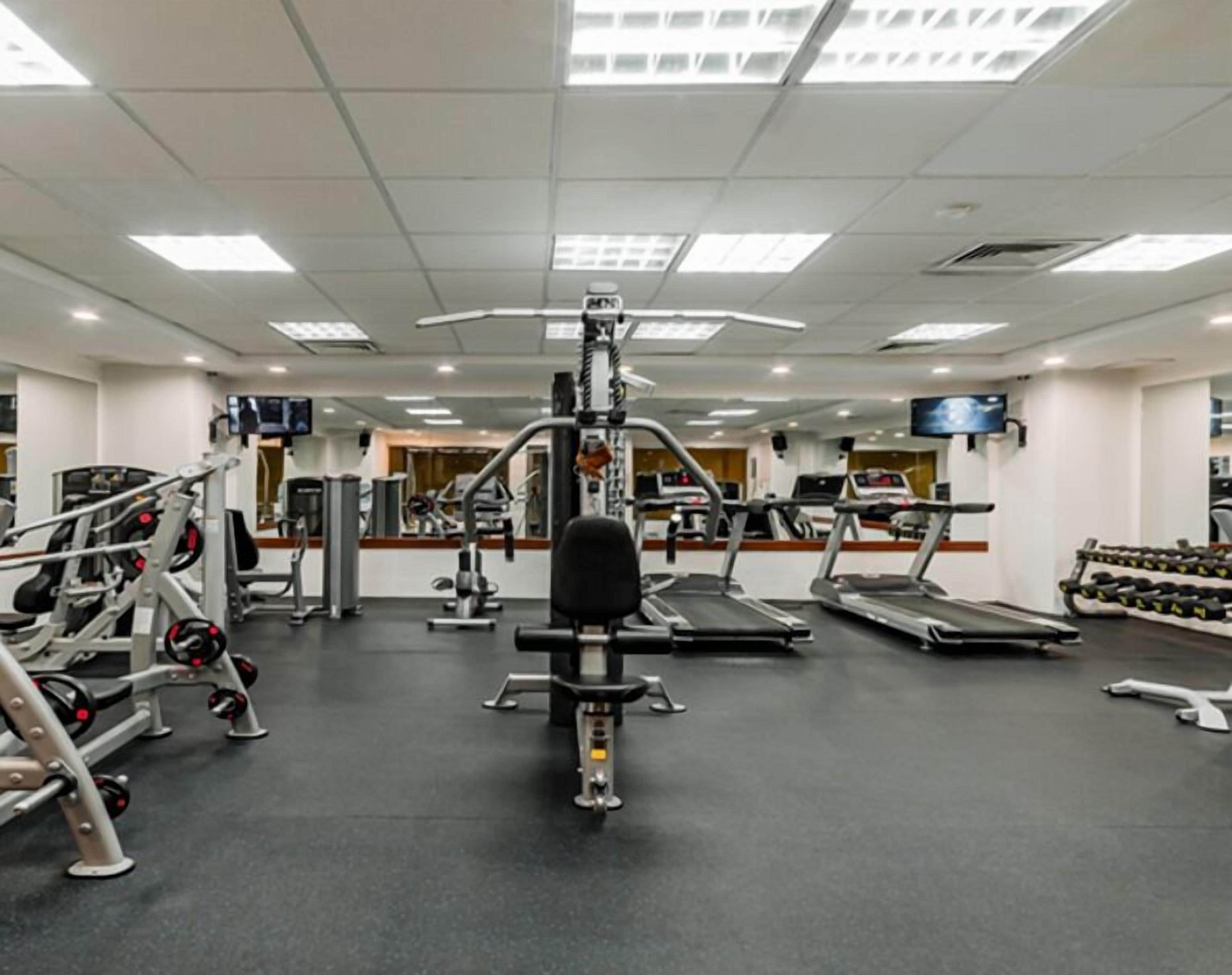 A gym with treadmills, weight machines, and dumbbells.