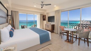 Une chambre d’hôtel comprenant un lit, un bureau, une chaise, une télévision et un balcon avec vue sur l’océan.