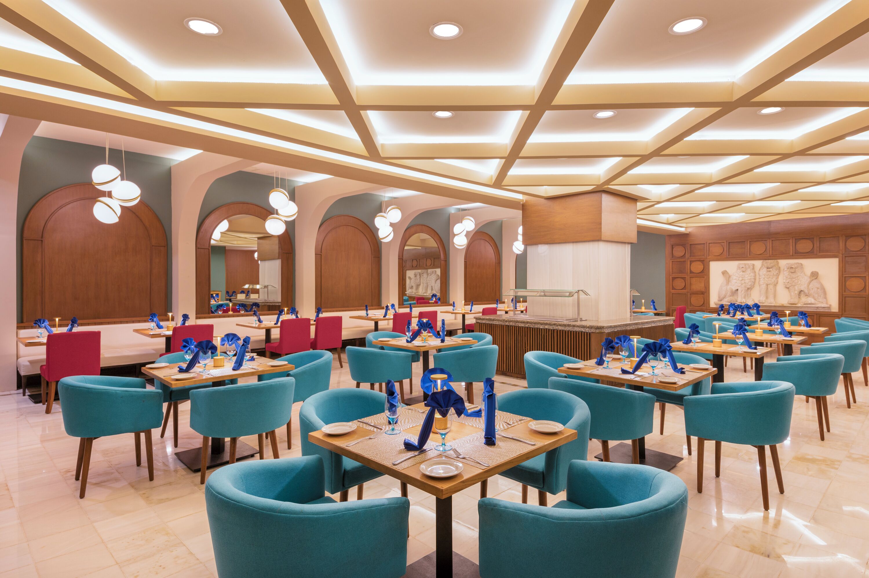 Un vaste espace dédié à la salle à manger, avec de nombreuses tables et chaises, un bar central et un design moderne au niveau du plafond.