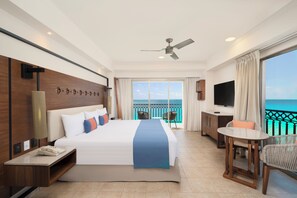 A hotel room with a bed, a desk, a chair, a TV, and a balcony with a view. - GR Solaris Cancun & Spa - All Inclusive (Cancun)