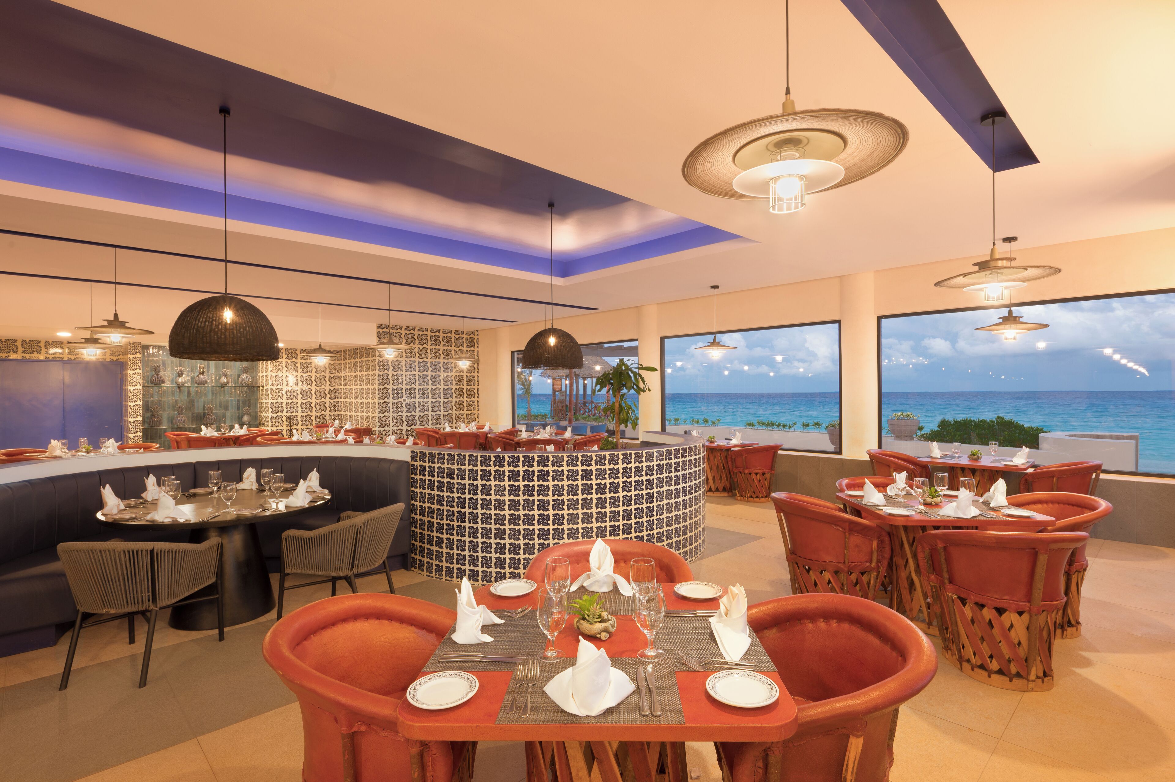 A restaurant with a curved bar, round tables, and chairs.