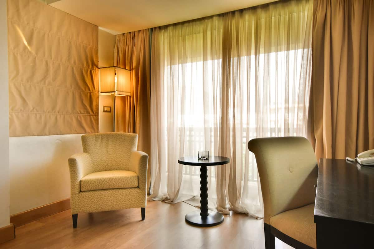 A hotel room with a sofa, a small round table, and a chair.