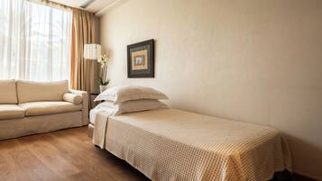 Habitación de hotel con cama, sofá, lámpara y un cuadro en la pared.
